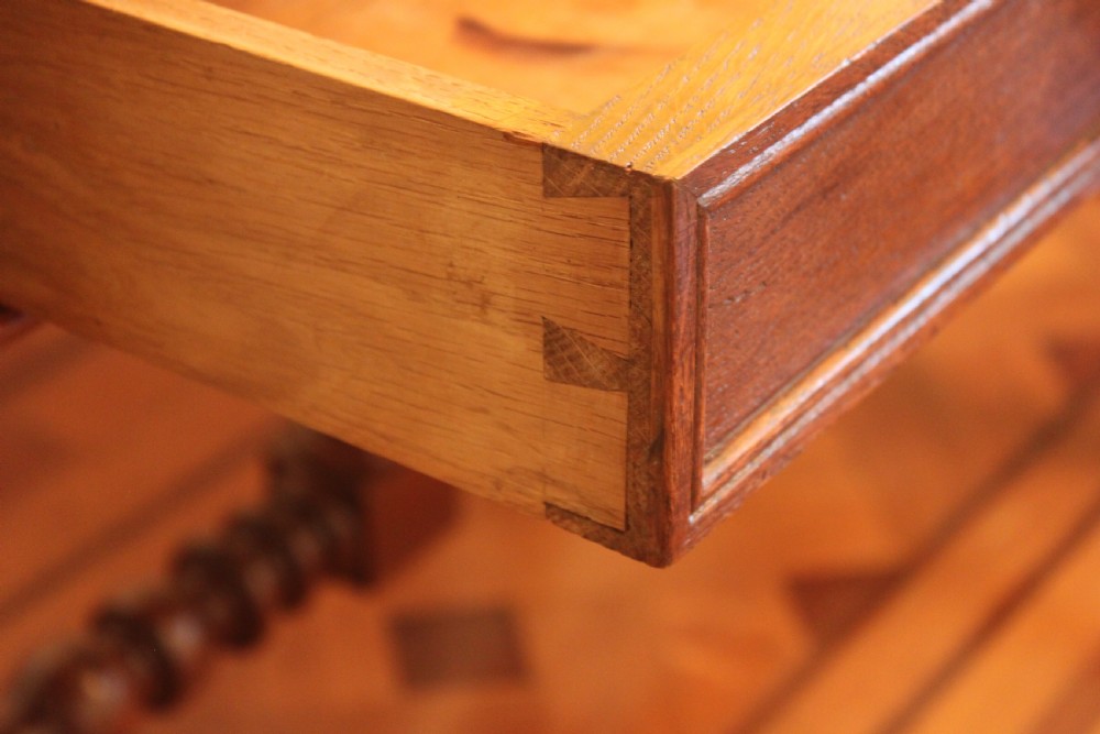 An antique French oak writing desk featuring a gold-tooled dark leather top insert, frieze drawers, turned baluster legs, and a stretcher base with a central finial. View XI