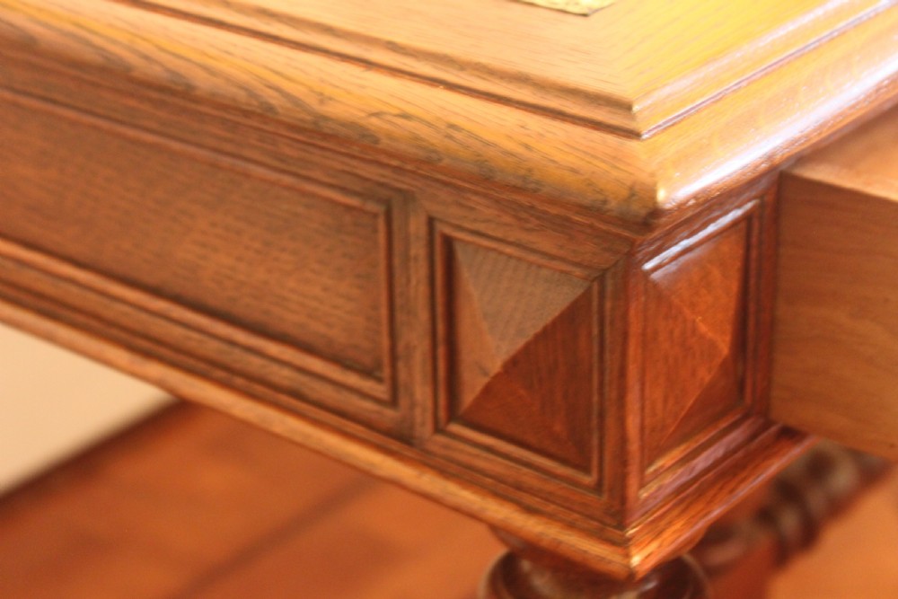 An antique French oak writing desk featuring a gold-tooled dark leather top insert, frieze drawers, turned baluster legs, and a stretcher base with a central finial. View XII