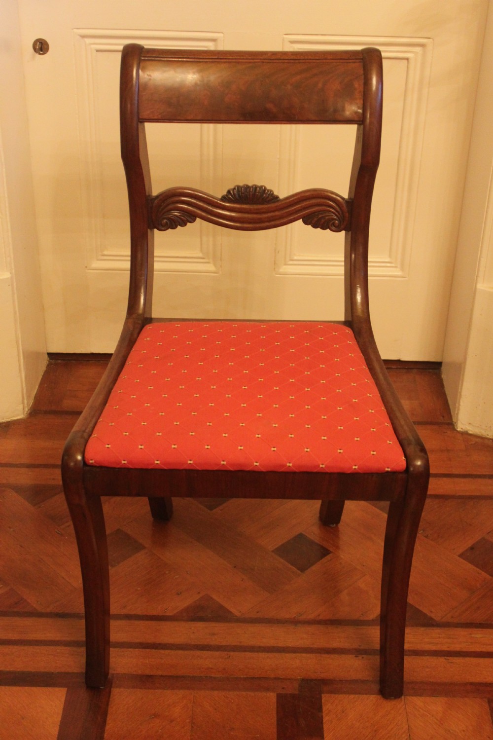 A set of six Regency mahogany dining chairs featuring carved crest rails and red patterned upholstered seats. View III