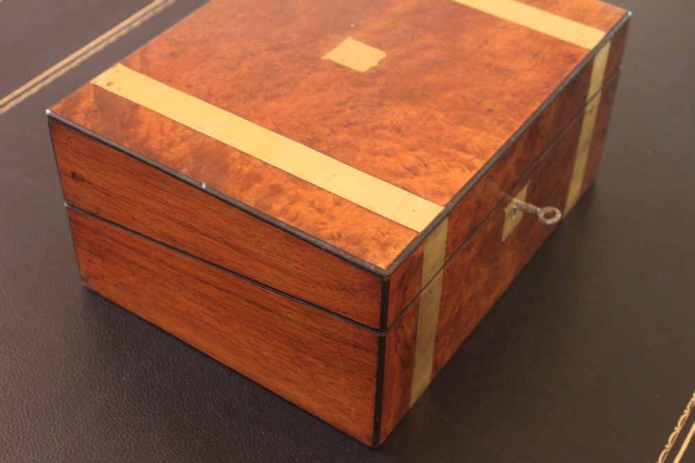 A closed rectangular Victorian burr walnut writing slope decorated with two wide brass straps and a central brass shield inlay. View III