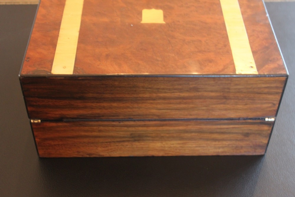A closed rectangular Victorian burr walnut writing slope decorated with two wide brass straps and a central brass shield inlay. View V