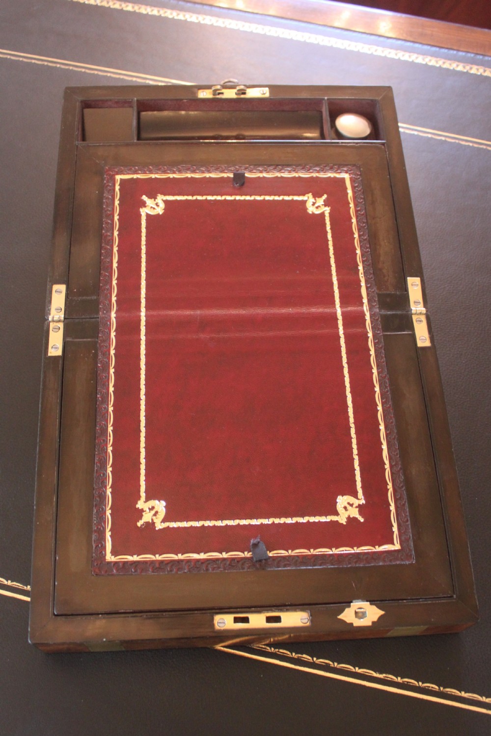 A closed rectangular Victorian burr walnut writing slope decorated with two wide brass straps and a central brass shield inlay. View VI