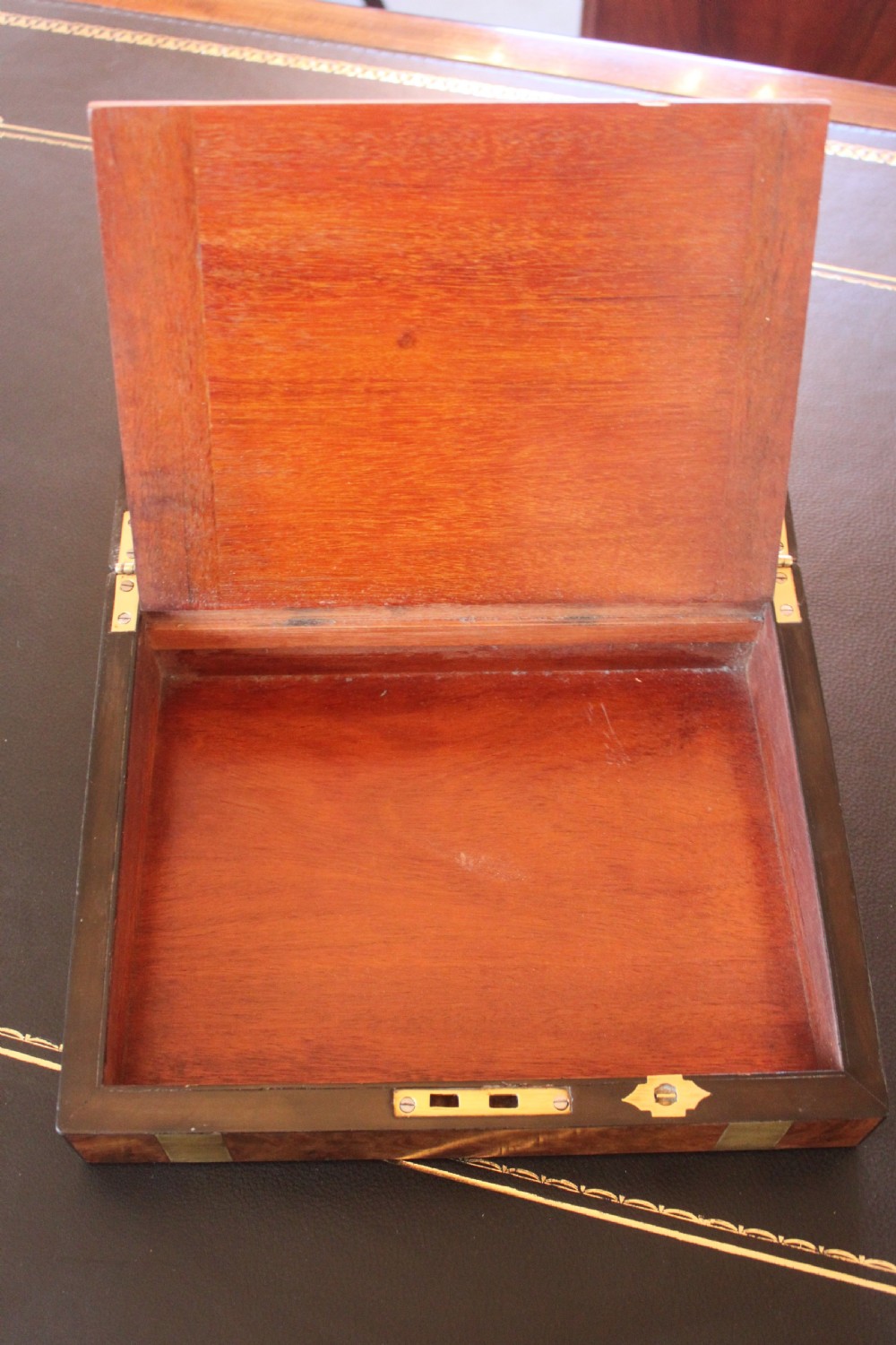A closed rectangular Victorian burr walnut writing slope decorated with two wide brass straps and a central brass shield inlay. View VIII