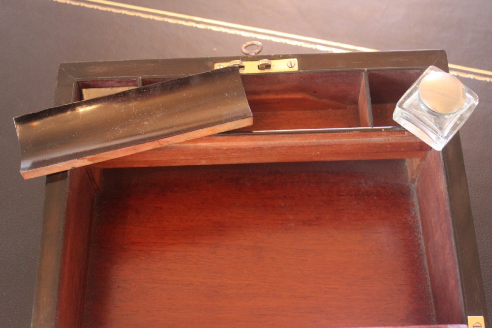 A closed rectangular Victorian burr walnut writing slope decorated with two wide brass straps and a central brass shield inlay. View X
