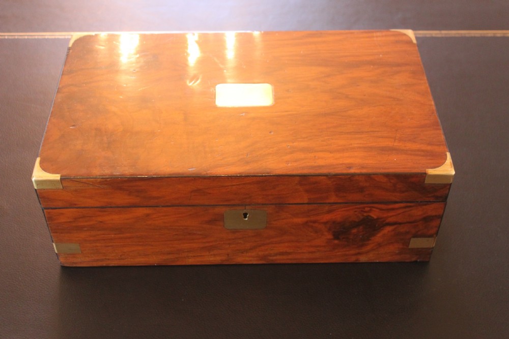 A closed rectangular Victorian writing slope constructed from figured walnut with brass corner mounts and a brass lock escutcheon.