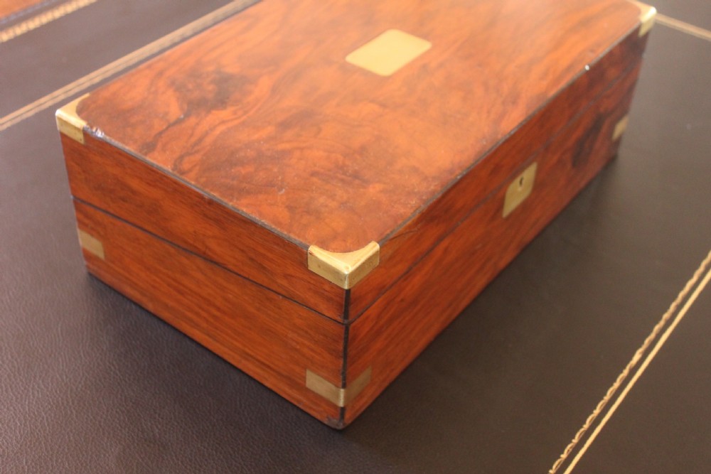 A closed rectangular Victorian writing slope constructed from figured walnut with brass corner mounts and a brass lock escutcheon. View II