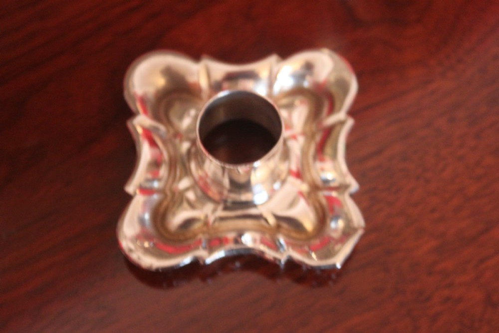 A pair of Victorian silver-plated candlesticks with ornate scroll motifs on square bases and tapered stems. View V