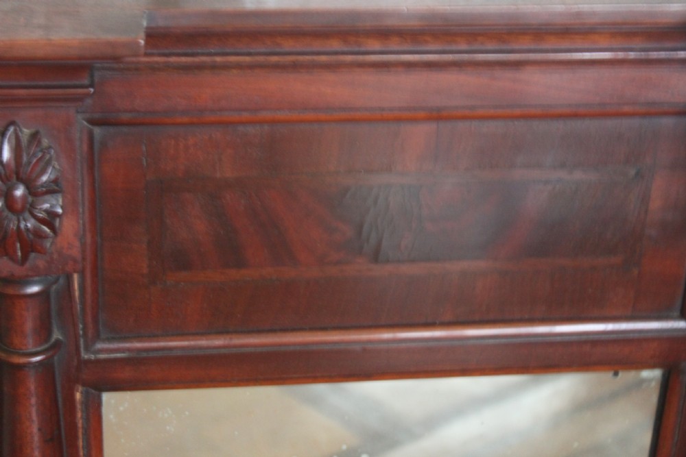 A George IV mahogany pier mirror featuring turned side columns, carved rosettes, a stepped cornice, and an aged glass plate. View IV