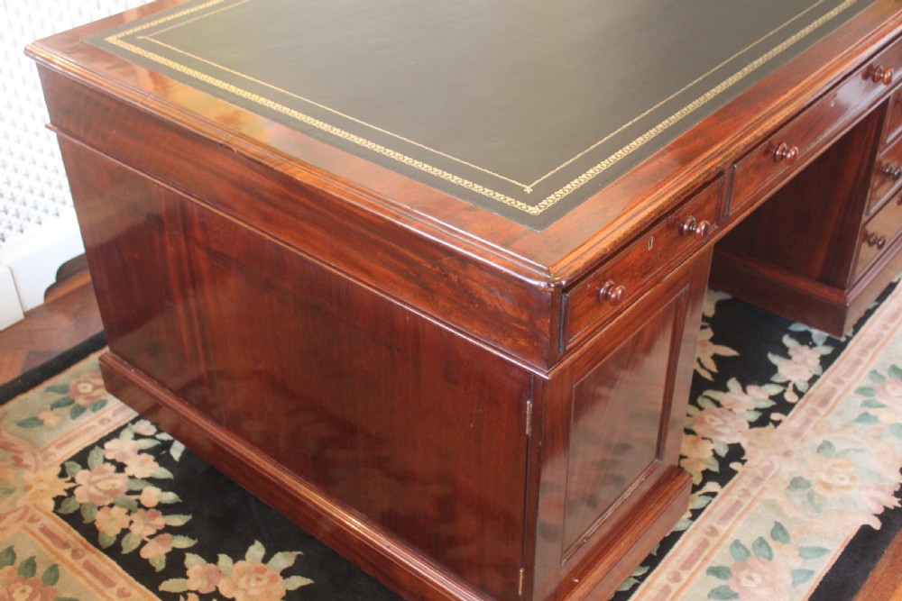 A Victorian mahogany partners desk featuring a green gilded leather writing surface and pedestals with turned wooden drawer knobs. View II
