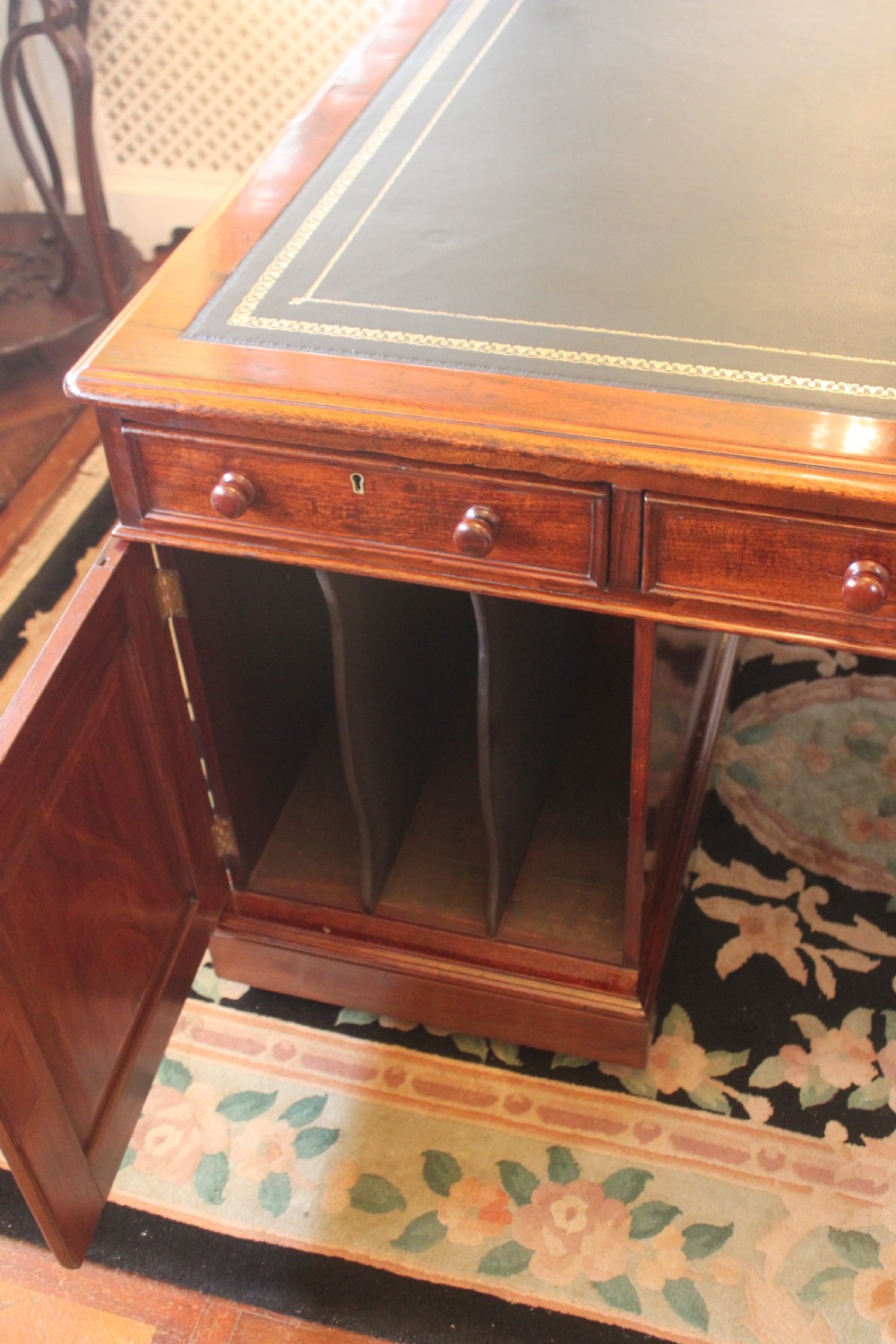 A Victorian mahogany partners desk featuring a green gilded leather writing surface and pedestals with turned wooden drawer knobs. View V