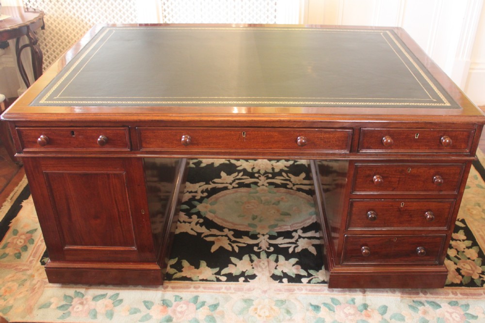 A Victorian mahogany partners desk featuring a green gilded leather writing surface and pedestals with turned wooden drawer knobs. View VI