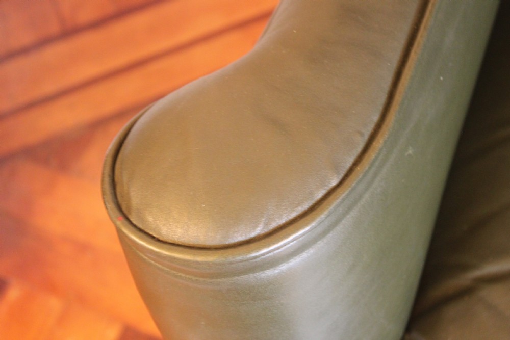 A late nineteenth or early twentieth century Queen Anne style wingback armchair upholstered in olive green leather with carved cabriole legs. View VIII