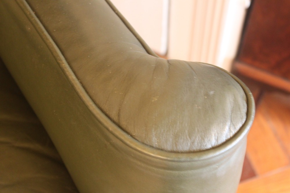 A late nineteenth or early twentieth century Queen Anne style wingback armchair upholstered in olive green leather with carved cabriole legs. View IX