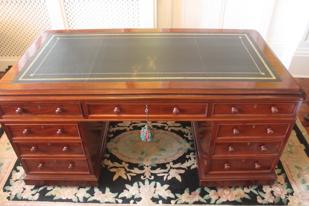 A Victorian mahogany partners desk featuring a dark leather writing insert, multiple pedestal drawers with turned wooden knobs, and a central frieze drawer. View II