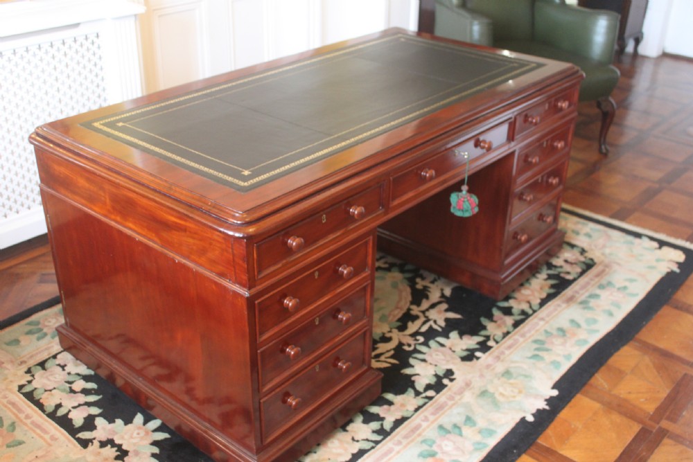 A Victorian mahogany partners desk featuring a dark leather writing insert, multiple pedestal drawers with turned wooden knobs, and a central frieze drawer. View III