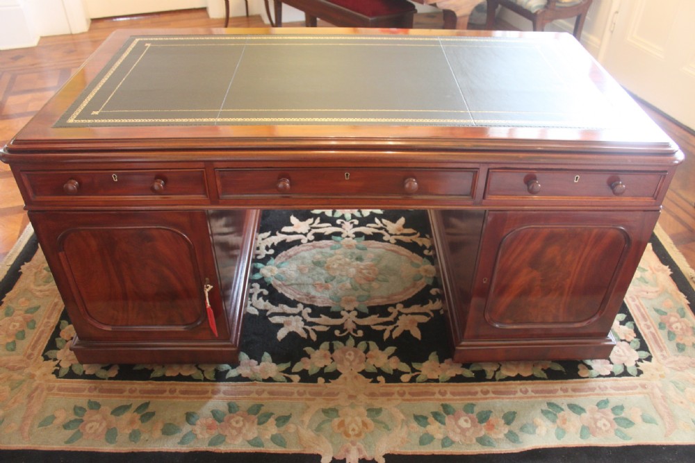 A Victorian mahogany partners desk featuring a dark leather writing insert, multiple pedestal drawers with turned wooden knobs, and a central frieze drawer. View VI