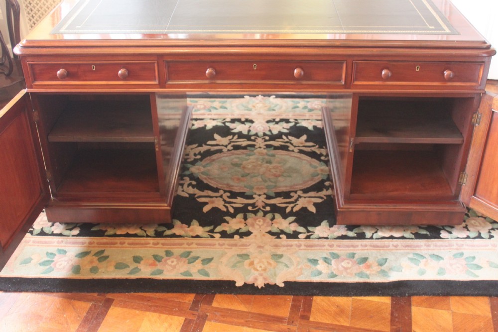 A Victorian mahogany partners desk featuring a dark leather writing insert, multiple pedestal drawers with turned wooden knobs, and a central frieze drawer. View XIII