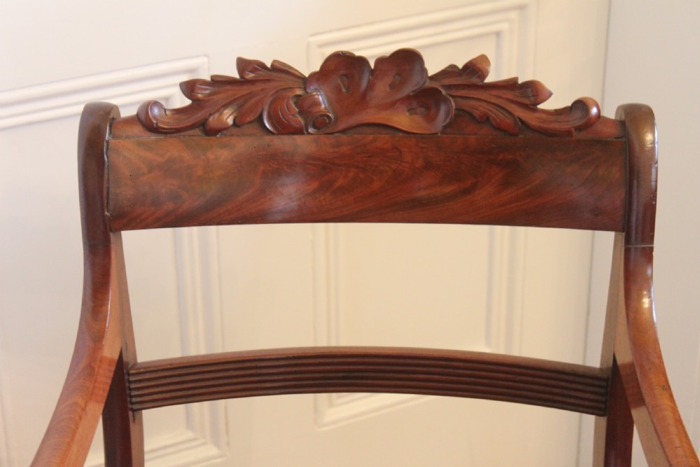 A Regency mahogany armchair featuring a carved crest rail, scrolled reeded arms, sabre front legs, and dragonfly pattern upholstery. View IV