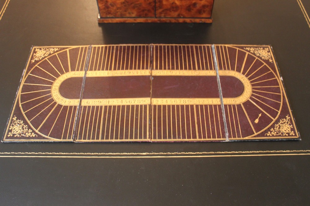 An opened Victorian burr walnut games compendium displaying wooden chess pieces, draughts, cribbage board, and an inlaid game board attached inside the lid. View XVII