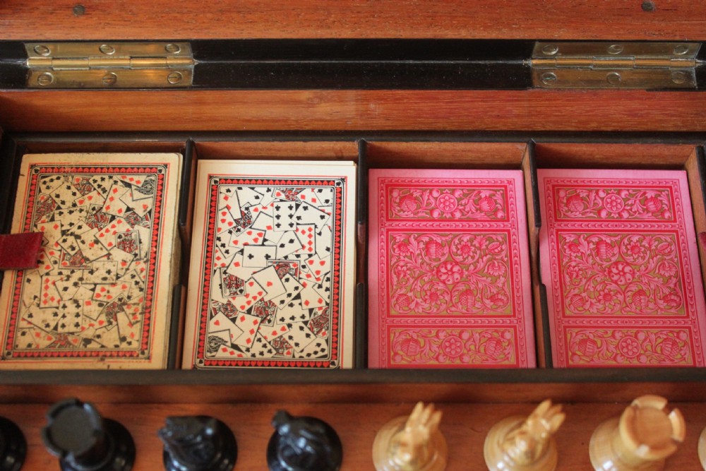 An opened Victorian burr walnut games compendium displaying wooden chess pieces, draughts, cribbage board, and an inlaid game board attached inside the lid. View XIX