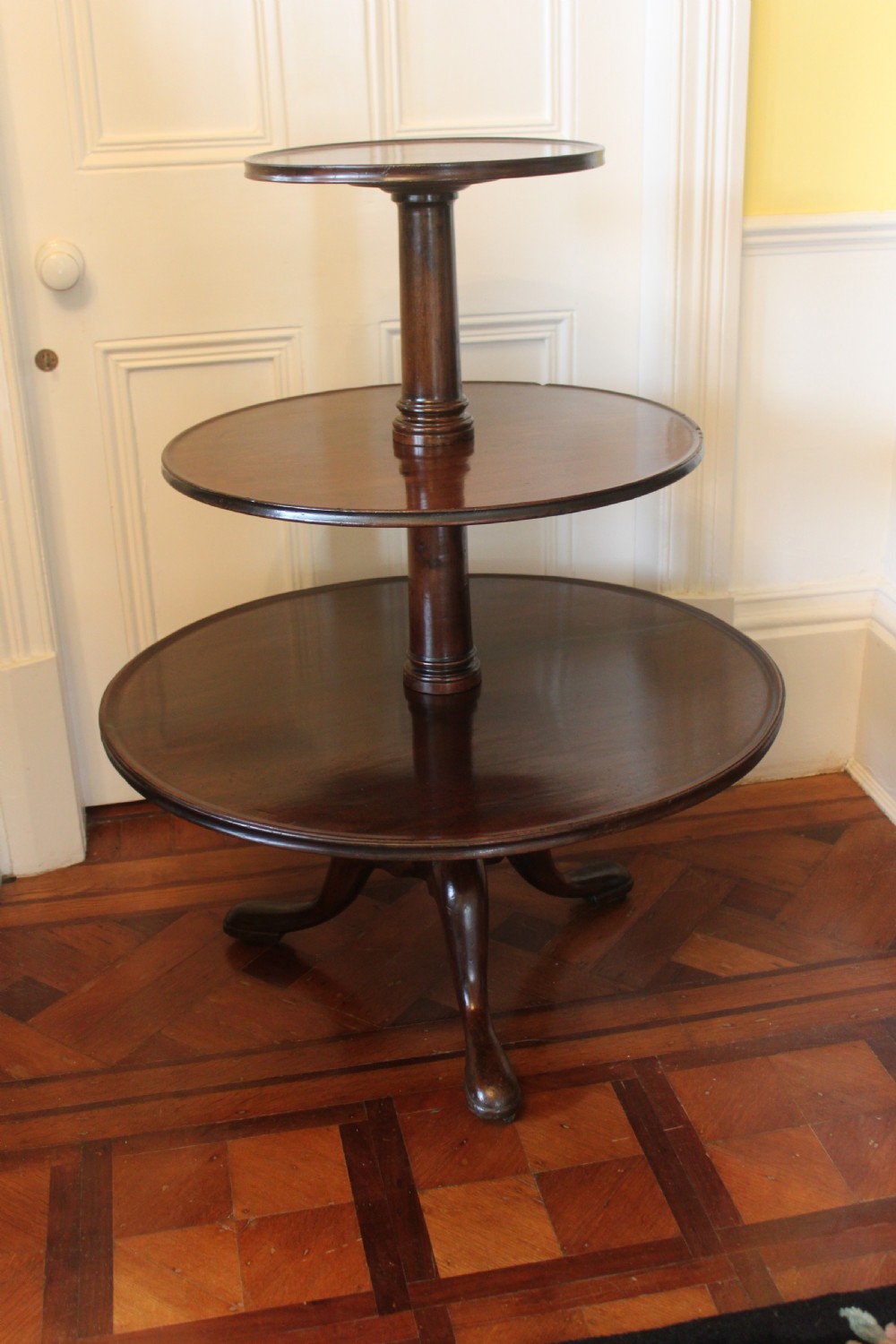 A three-tier Georgian mahogany dumb waiter featuring graduated revolving circular surfaces on a turned central column with a tripod base. View III