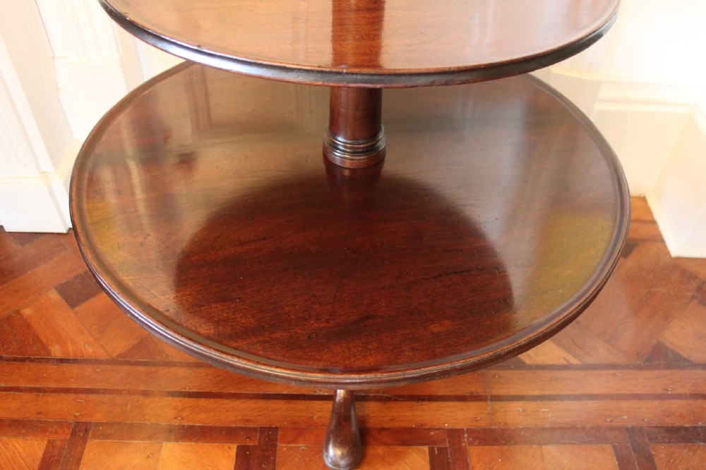 A three-tier Georgian mahogany dumb waiter featuring graduated revolving circular surfaces on a turned central column with a tripod base. View X
