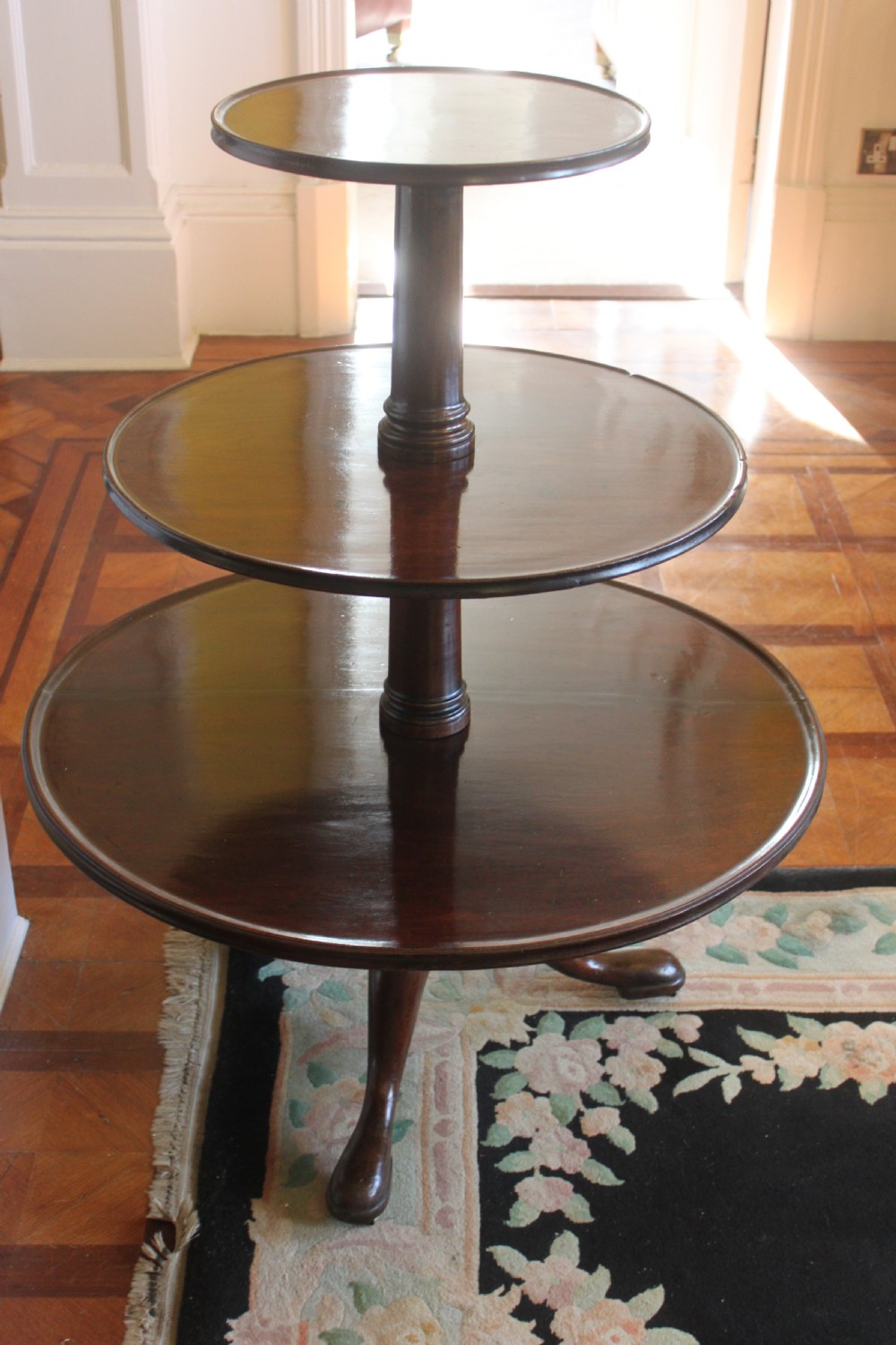 A three-tier Georgian mahogany dumb waiter featuring graduated revolving circular surfaces on a turned central column with a tripod base. View XI