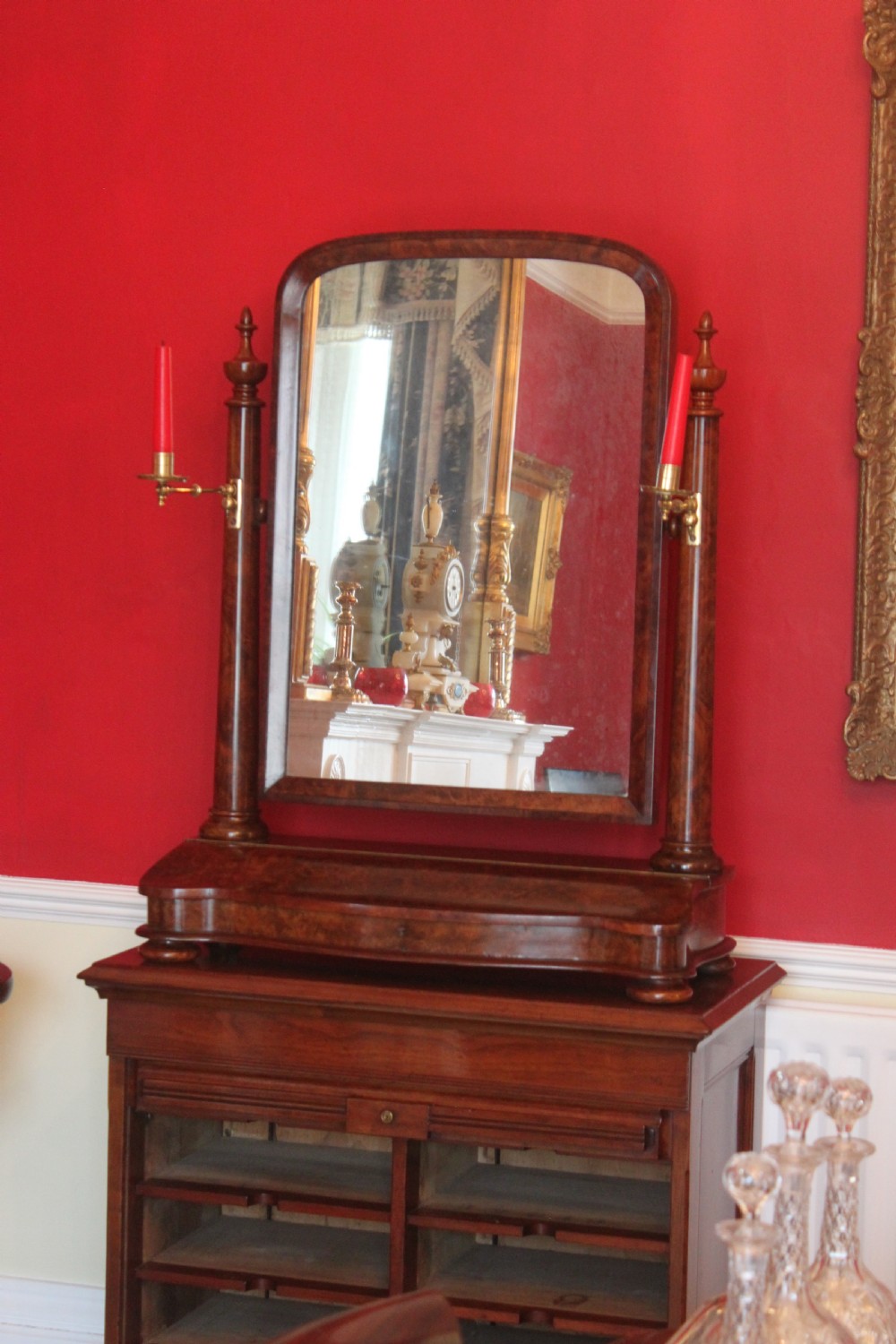 A Victorian burr walnut toilet mirror featuring a tilting arched glass frame set between turned columns with extended brass candle sconces on a shaped plinth base. View IX