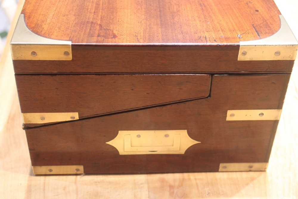 A closed rectangular late Georgian mahogany campaign writing slope featuring flush brass corner brackets, protective straps, and a decorative brass keyhole escutcheon. View III