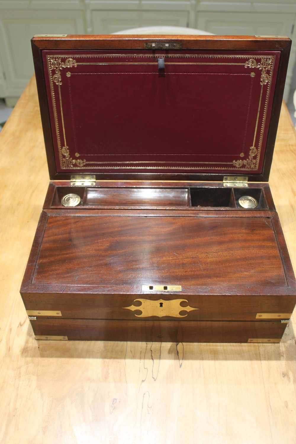 A closed rectangular late Georgian mahogany campaign writing slope featuring flush brass corner brackets, protective straps, and a decorative brass keyhole escutcheon. View VI