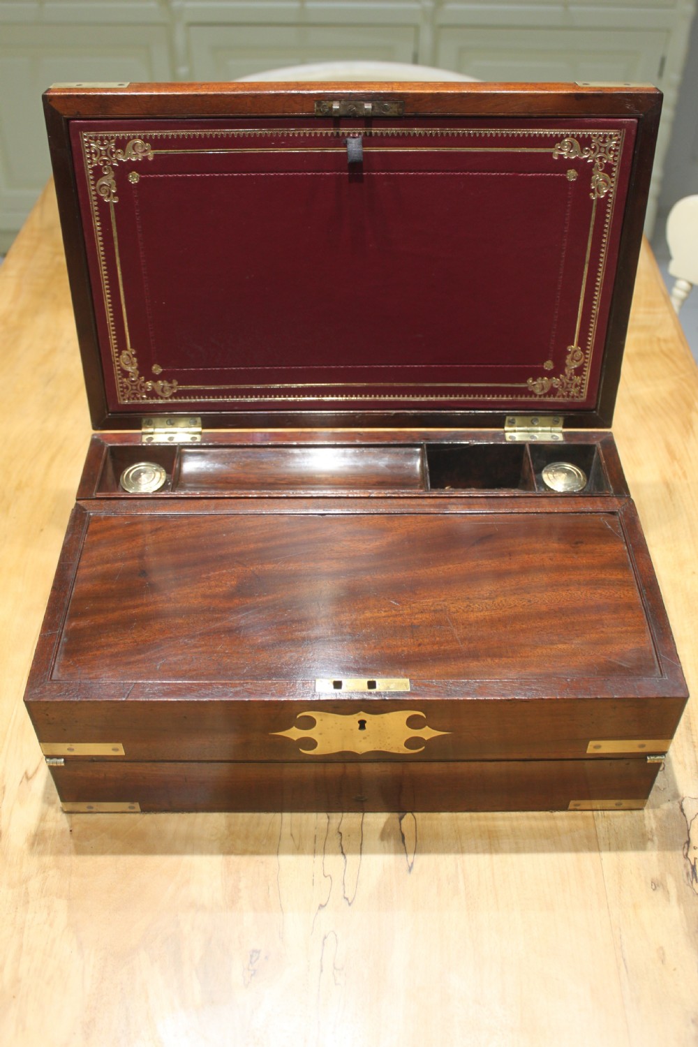 A closed rectangular late Georgian mahogany campaign writing slope featuring flush brass corner brackets, protective straps, and a decorative brass keyhole escutcheon. View VII