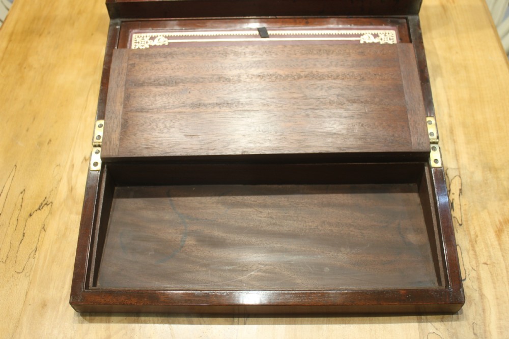 A closed rectangular late Georgian mahogany campaign writing slope featuring flush brass corner brackets, protective straps, and a decorative brass keyhole escutcheon. View IX