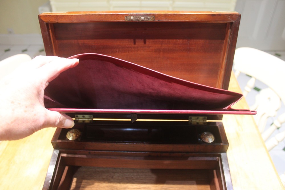 A closed rectangular late Georgian mahogany campaign writing slope featuring flush brass corner brackets, protective straps, and a decorative brass keyhole escutcheon. View XI