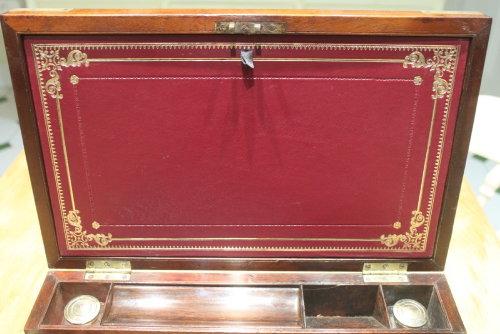 A closed rectangular late Georgian mahogany campaign writing slope featuring flush brass corner brackets, protective straps, and a decorative brass keyhole escutcheon. View XII
