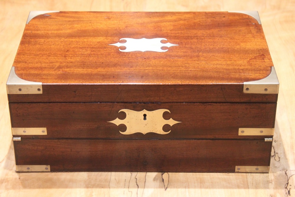 A closed rectangular late Georgian mahogany campaign writing slope featuring flush brass corner brackets, protective straps, and a decorative brass keyhole escutcheon. View XIX