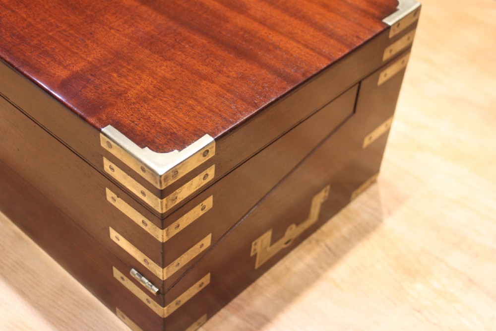 A 19th-century rectangular mahogany campaign writing slope with flush brass corner brackets, brass side strapping, an inlaid brass keyhole escutcheon, and a central brass plaque on the lid. View II