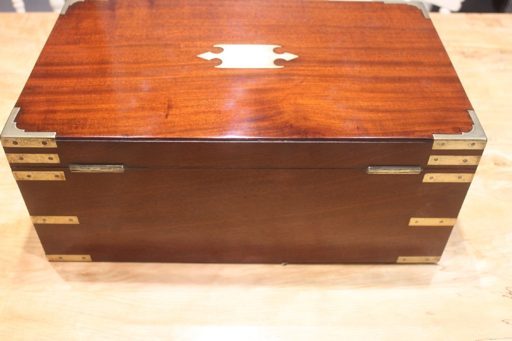 A 19th-century rectangular mahogany campaign writing slope with flush brass corner brackets, brass side strapping, an inlaid brass keyhole escutcheon, and a central brass plaque on the lid. View IV