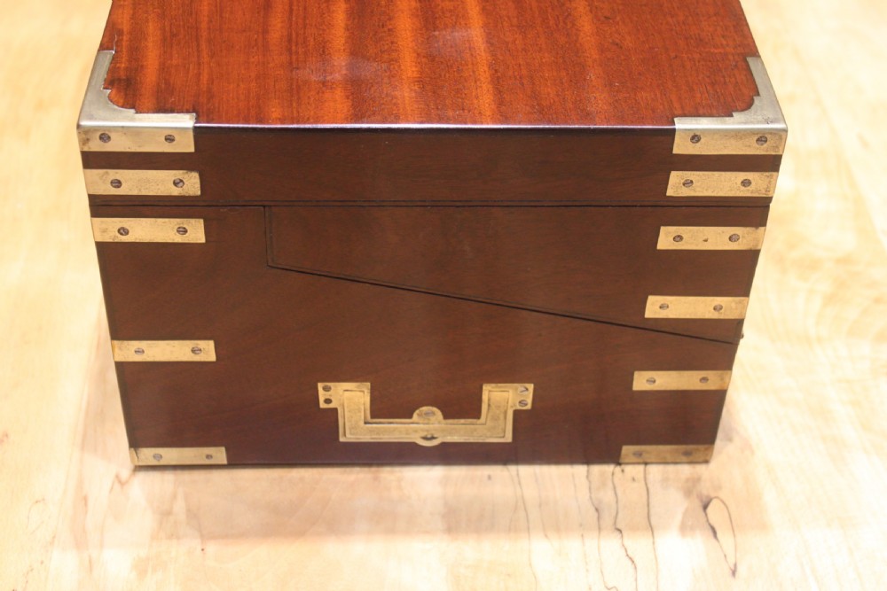 A 19th-century rectangular mahogany campaign writing slope with flush brass corner brackets, brass side strapping, an inlaid brass keyhole escutcheon, and a central brass plaque on the lid. View V