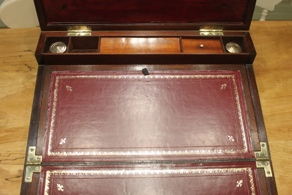A 19th-century rectangular mahogany campaign writing slope with flush brass corner brackets, brass side strapping, an inlaid brass keyhole escutcheon, and a central brass plaque on the lid. View VII