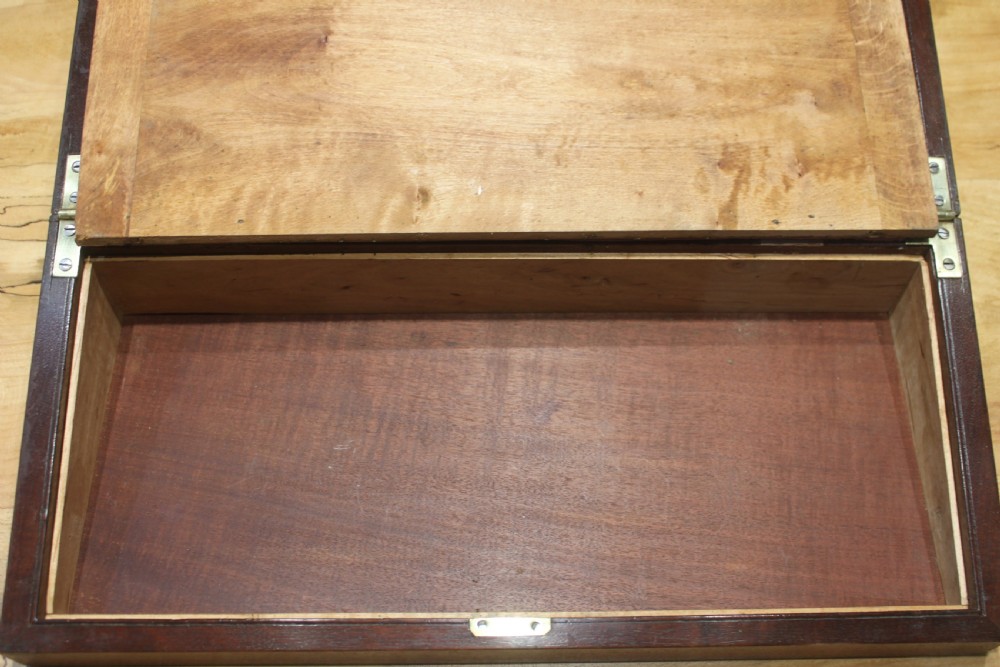 A 19th-century rectangular mahogany campaign writing slope with flush brass corner brackets, brass side strapping, an inlaid brass keyhole escutcheon, and a central brass plaque on the lid. View X