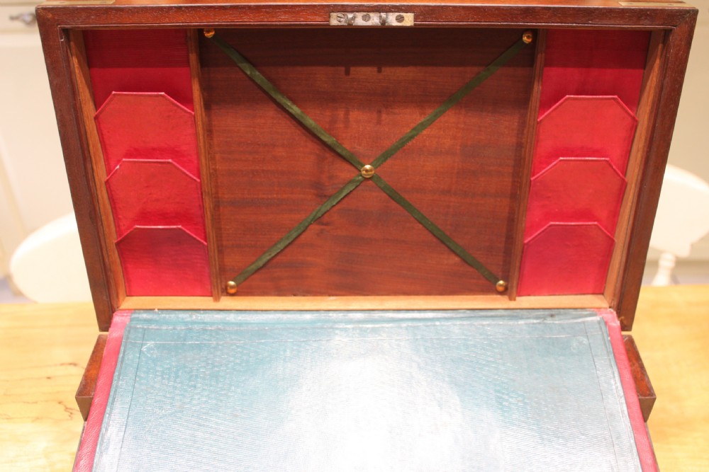A 19th-century rectangular mahogany campaign writing slope with flush brass corner brackets, brass side strapping, an inlaid brass keyhole escutcheon, and a central brass plaque on the lid. View XIV