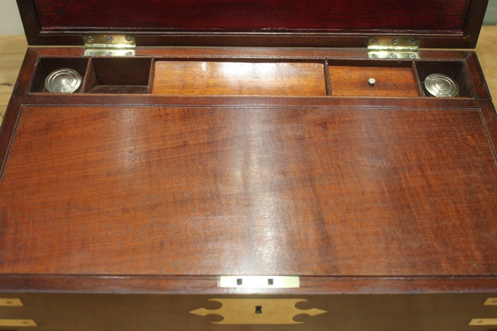 A 19th-century rectangular mahogany campaign writing slope with flush brass corner brackets, brass side strapping, an inlaid brass keyhole escutcheon, and a central brass plaque on the lid. View XVI