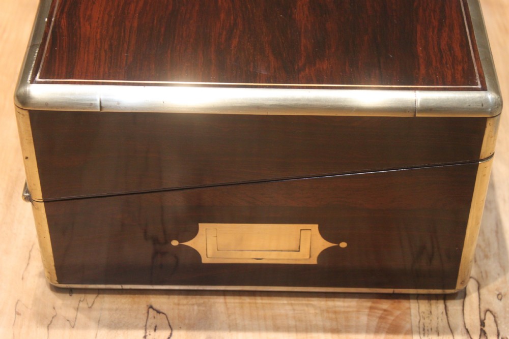 A closed rectangular dark rosewood writing slope featuring brass-bound corners, fine brass line inlay, a brass keyhole escutcheon, and an engraved central brass cartouche. View III