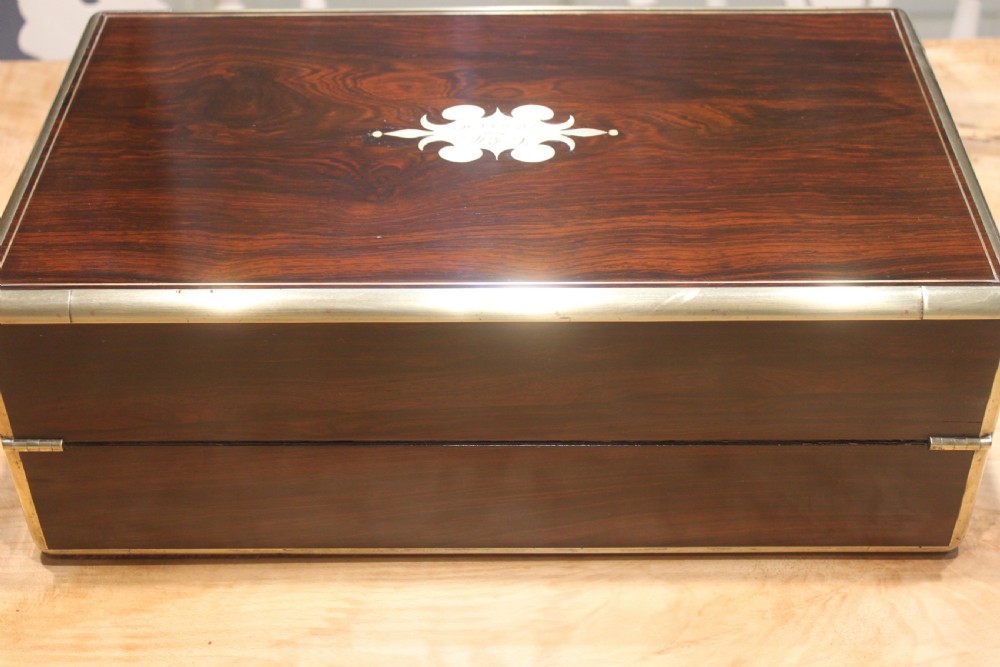 A closed rectangular dark rosewood writing slope featuring brass-bound corners, fine brass line inlay, a brass keyhole escutcheon, and an engraved central brass cartouche. View IV