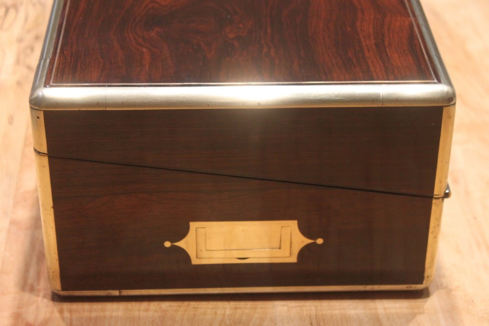 A closed rectangular dark rosewood writing slope featuring brass-bound corners, fine brass line inlay, a brass keyhole escutcheon, and an engraved central brass cartouche. View V
