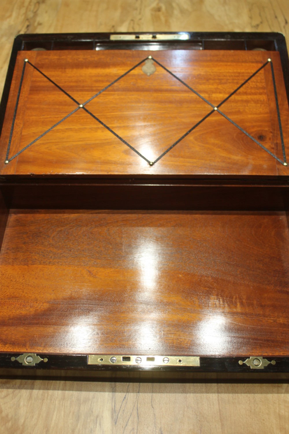A closed rectangular dark rosewood writing slope featuring brass-bound corners, fine brass line inlay, a brass keyhole escutcheon, and an engraved central brass cartouche. View X