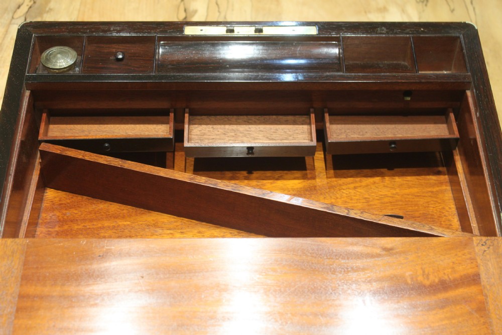 A closed rectangular dark rosewood writing slope featuring brass-bound corners, fine brass line inlay, a brass keyhole escutcheon, and an engraved central brass cartouche. View XIV