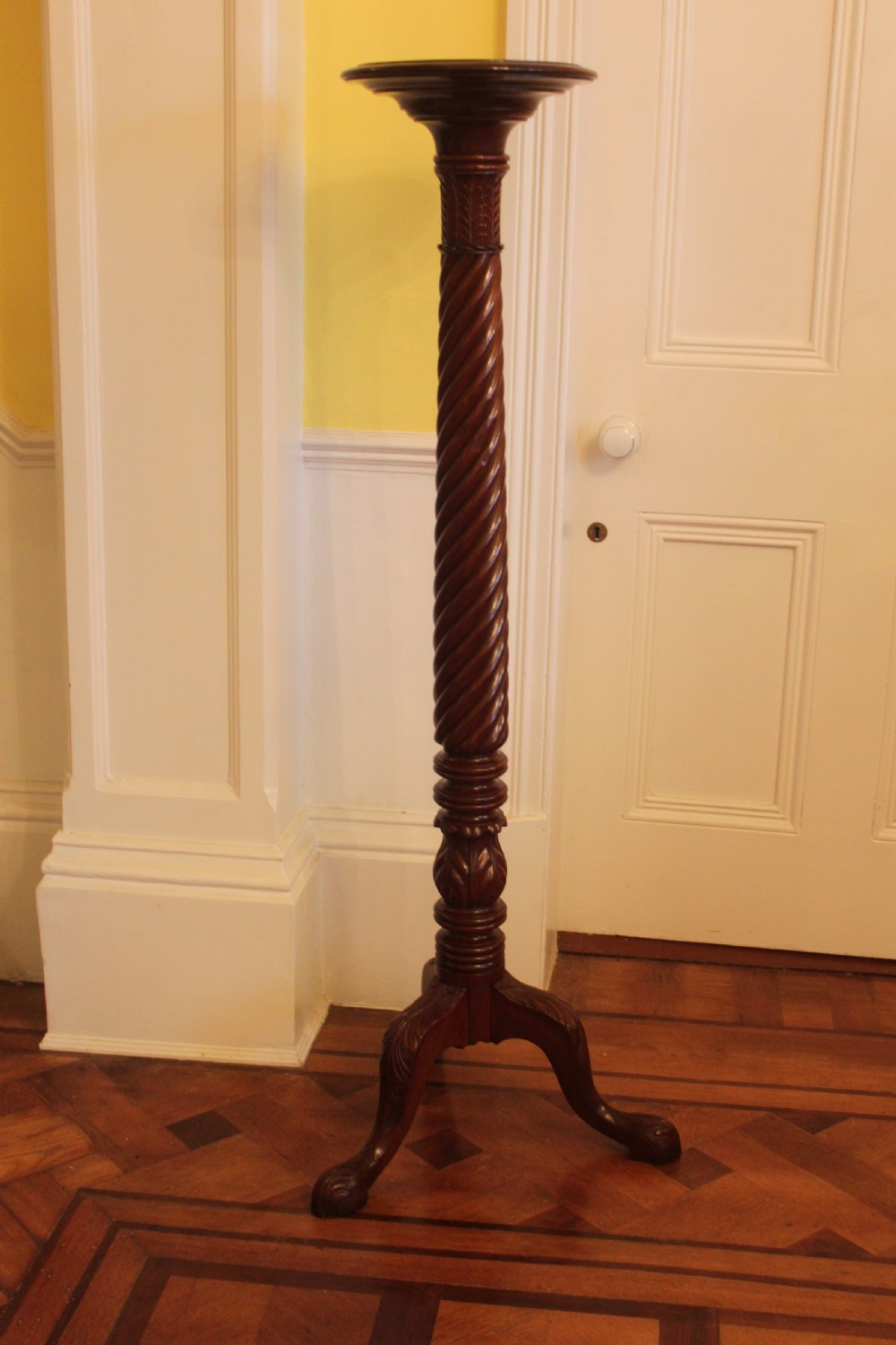 A tall nineteenth-century dark mahogany torchiere stand featuring a carved spiral twist column, acanthus leaf motifs, and a tripod base.