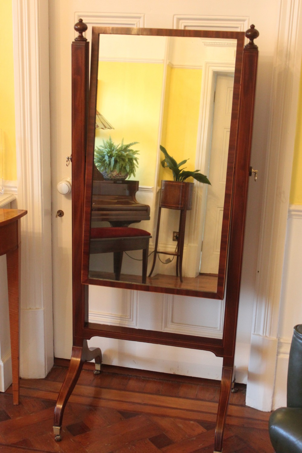 A full-length Sheraton style mahogany cheval dressing mirror with turned finials, splayed legs, brass castors, and a tilting frame. View II