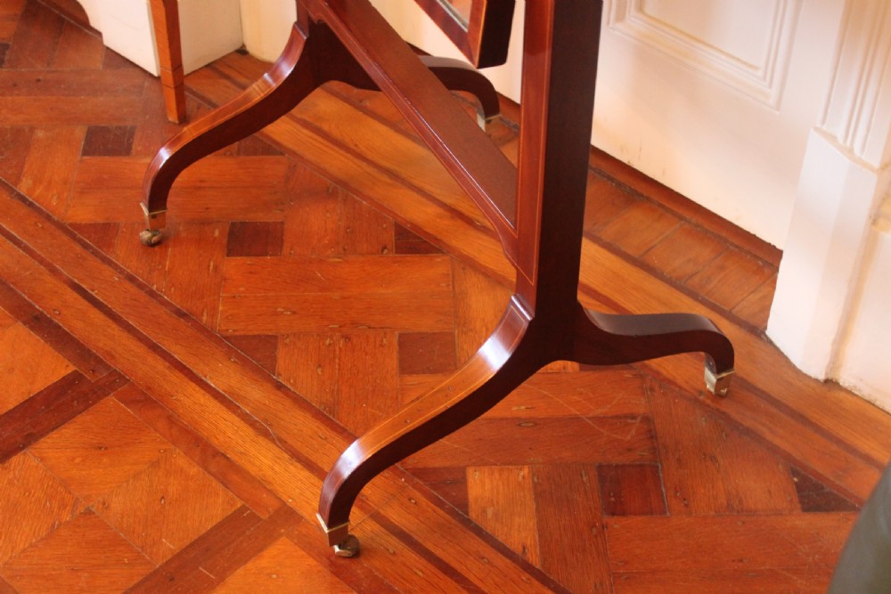 A full-length Sheraton style mahogany cheval dressing mirror with turned finials, splayed legs, brass castors, and a tilting frame. View III